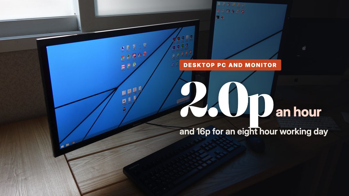 Two computer monitors and a keyboard on a wooden desk by a window