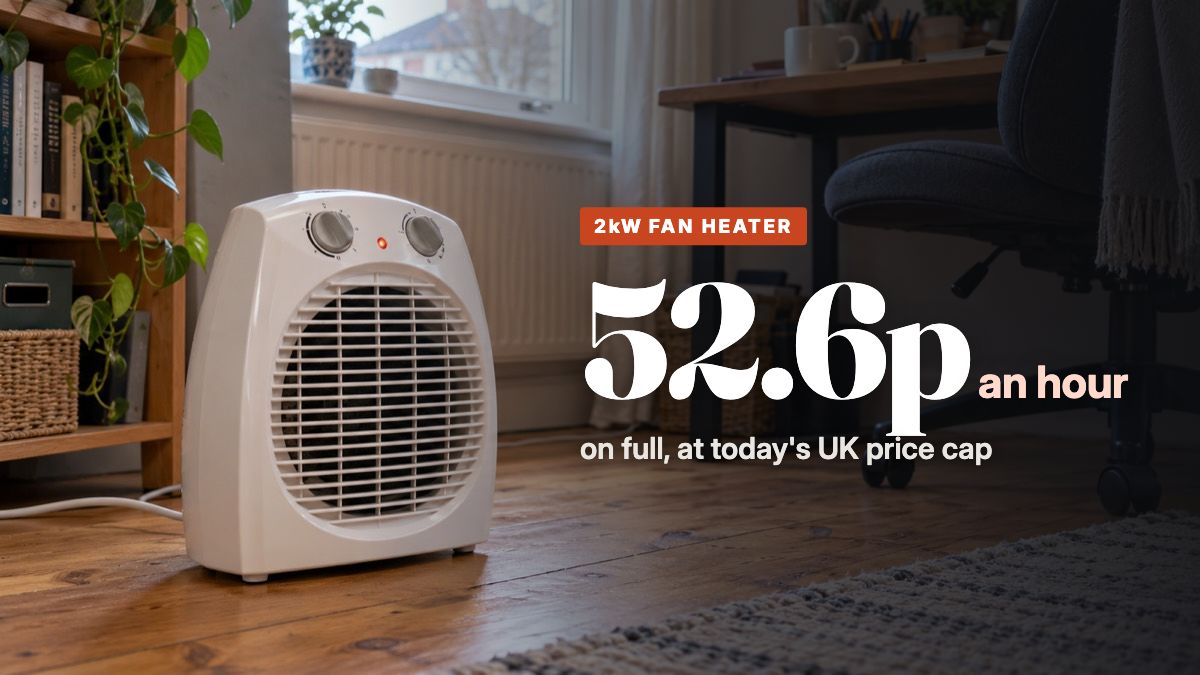 A small white 2kW fan heater on a wooden floor beside a desk in a UK home office